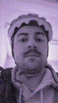 a selfie of a white person, wearing either headphones or a helmet, making an odd expression. the photo is edited to be colorized into a monochrome purple-ish color palette.
